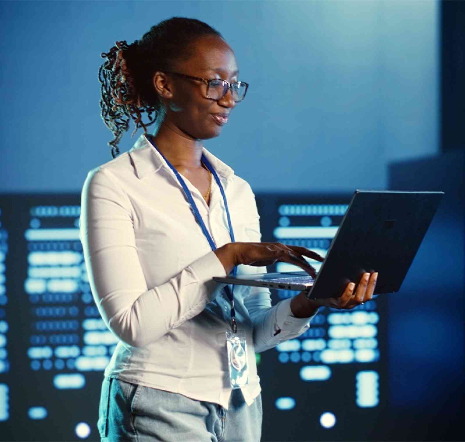 An IT professional works confidently in a modern office, focused on a computer screen displaying code and system interfaces, symbolizing expertise in information technology and system management.